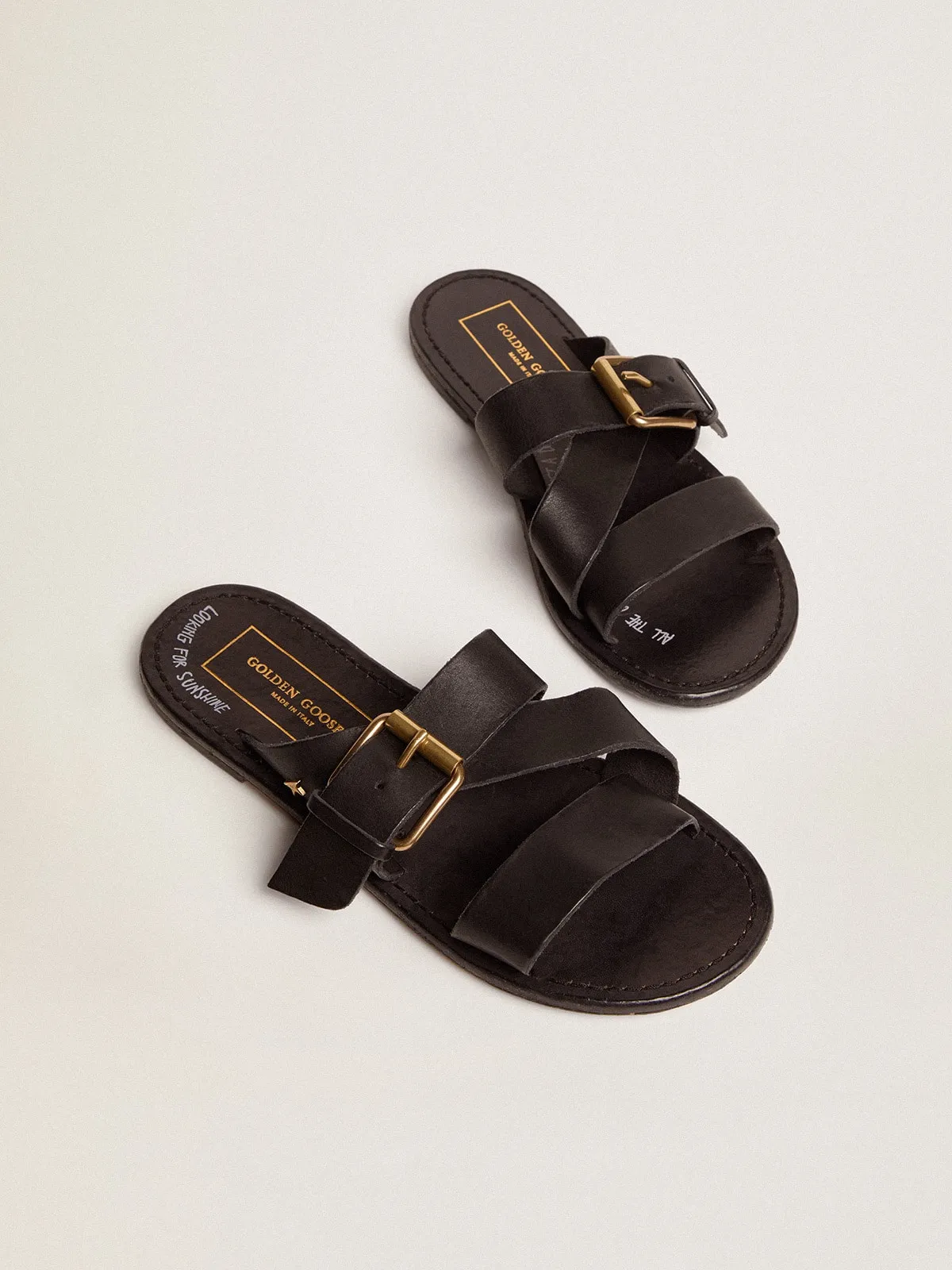 Women's flat sandals in black resin-coated leather