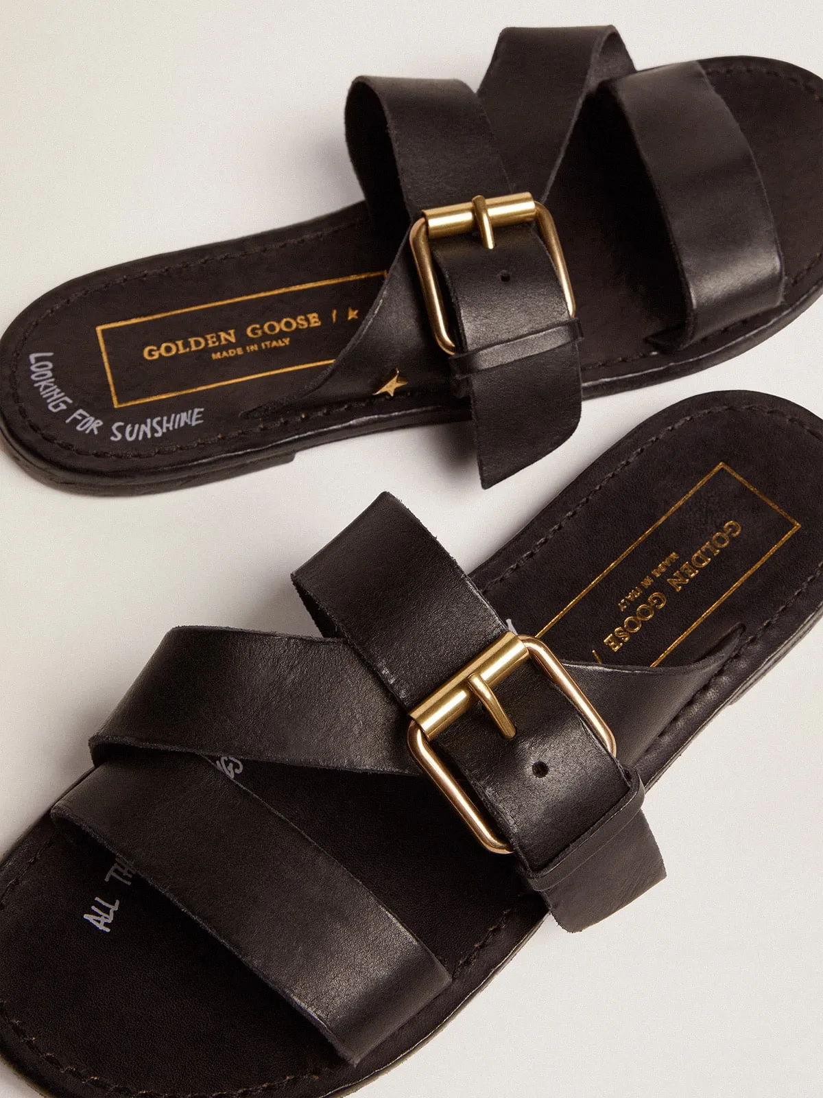 Women's flat sandals in black resin-coated leather